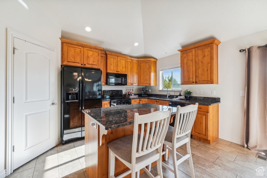 Kitchen with a center island, recessed lighting, brown cabinets, a sink, and black appliances