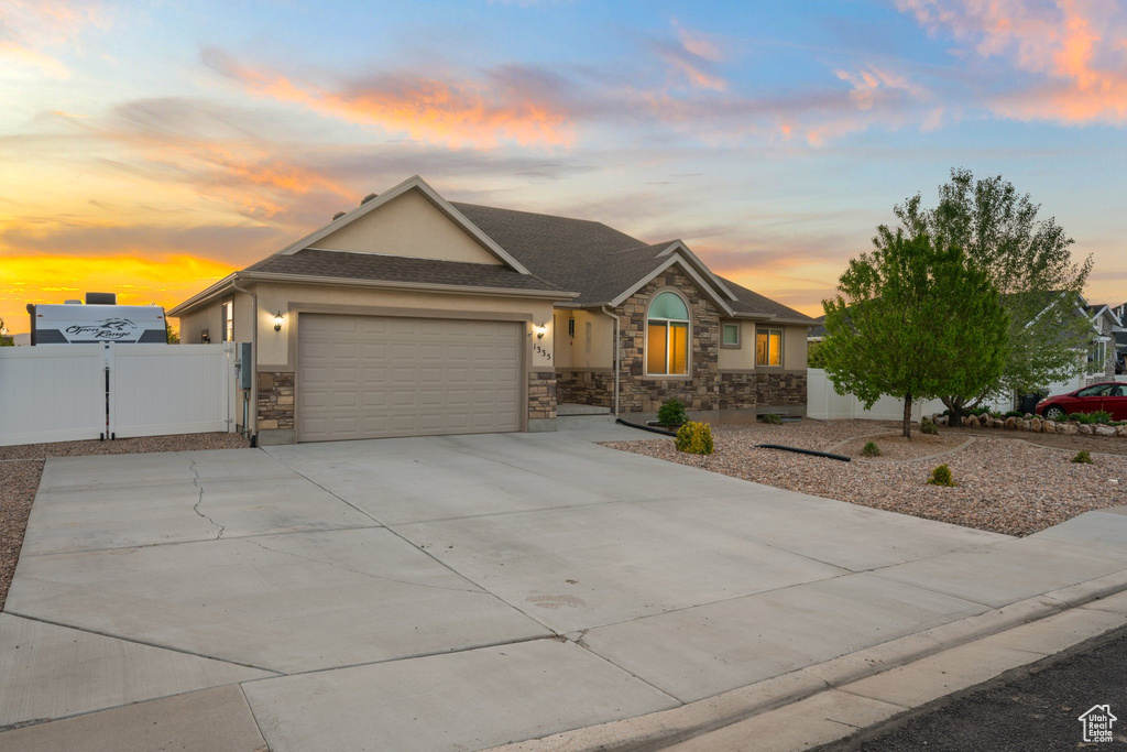 Single story home with fence, concrete driveway, an attached garage, stone siding, and stucco siding