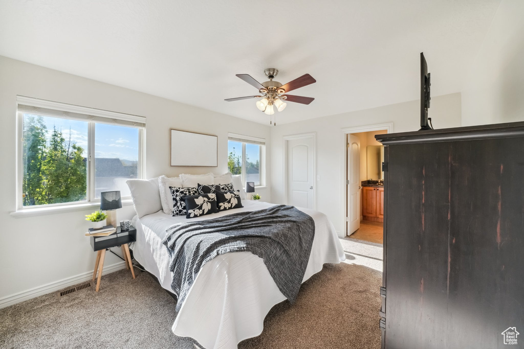 Bedroom with light colored carpet, baseboards, visible vents, and a ceiling fan