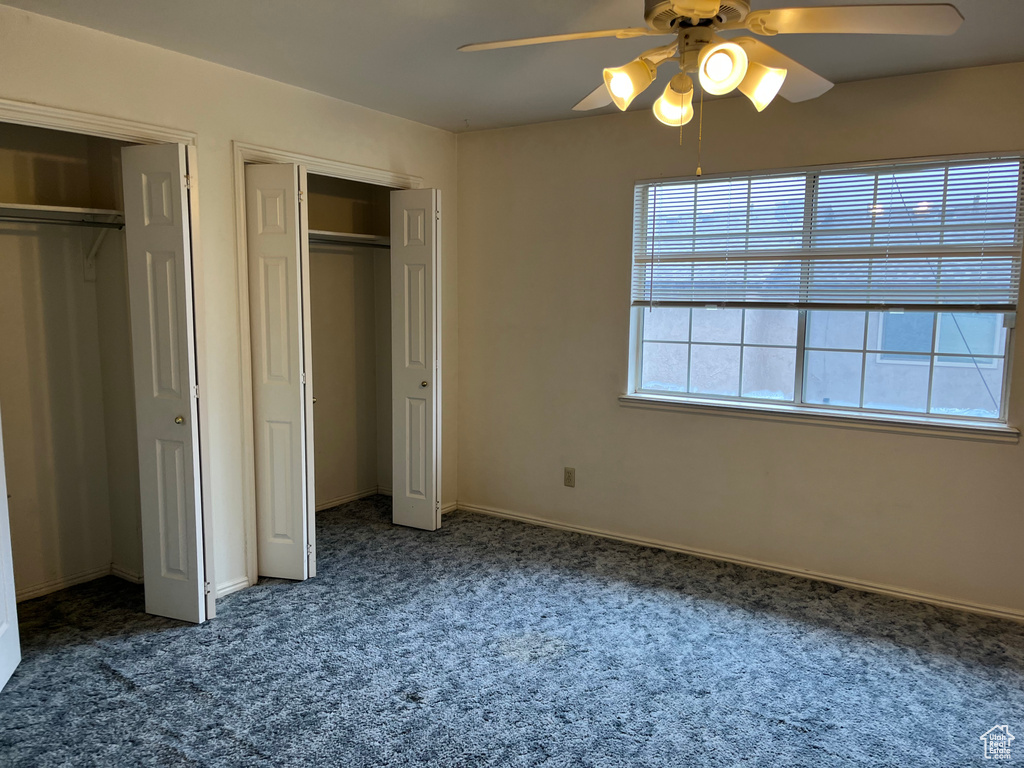 Unfurnished bedroom with baseboards, carpet flooring, multiple closets, and ceiling fan