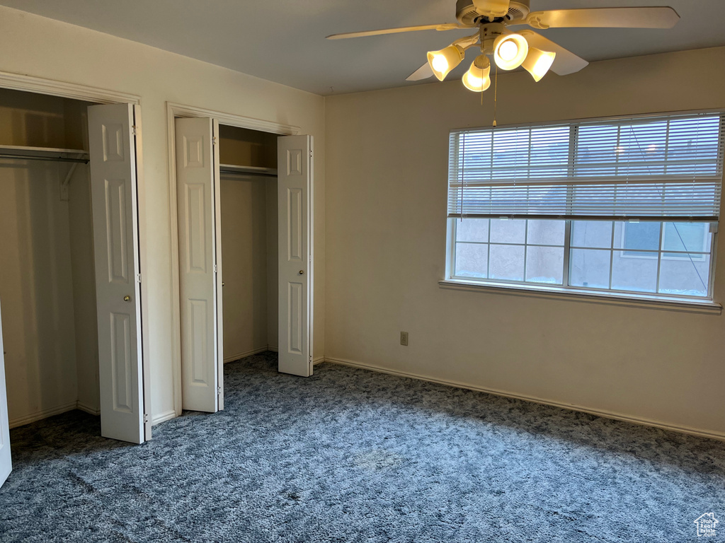 Unfurnished bedroom featuring multiple closets, baseboards, carpet, and a ceiling fan