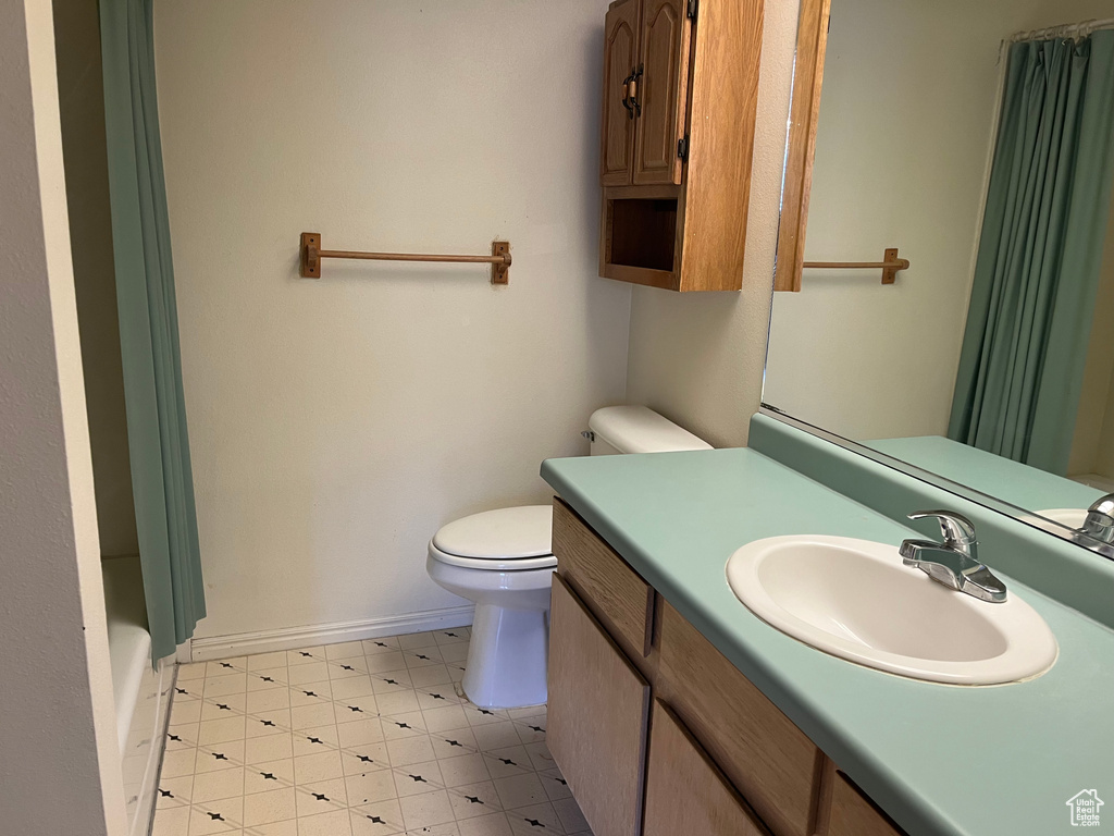 Bathroom featuring vanity, curtained shower, toilet, baseboards, and tile patterned floors