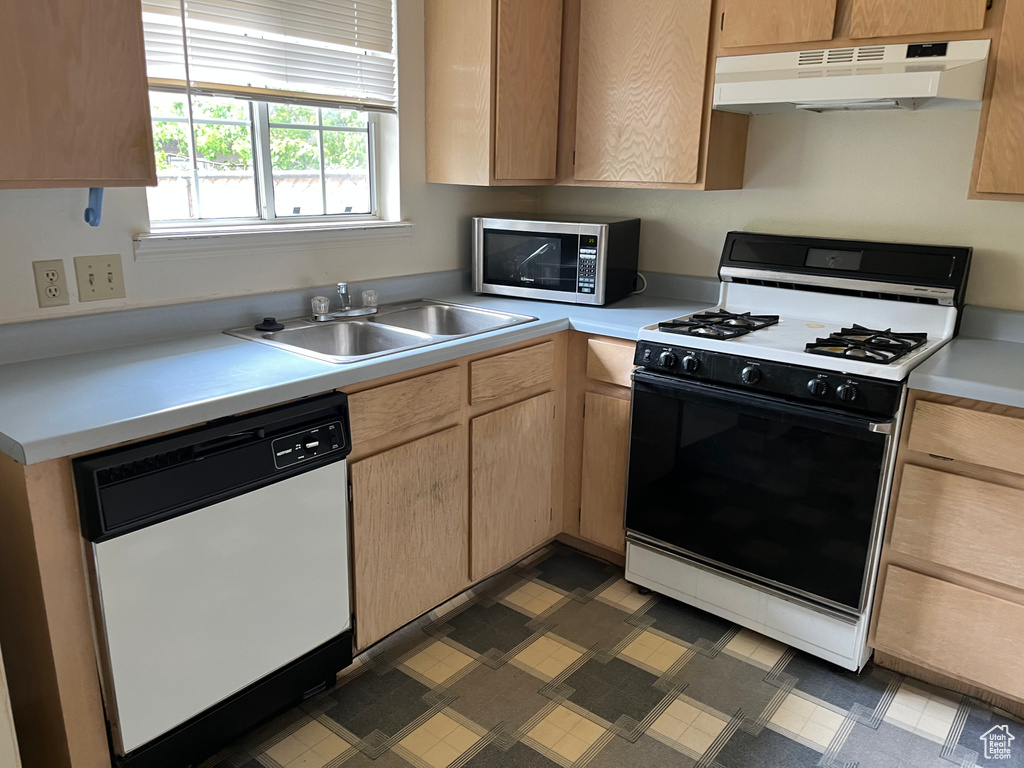 Kitchen with range with gas stovetop, light brown cabinets, stainless steel microwave, under cabinet range hood, and dishwasher