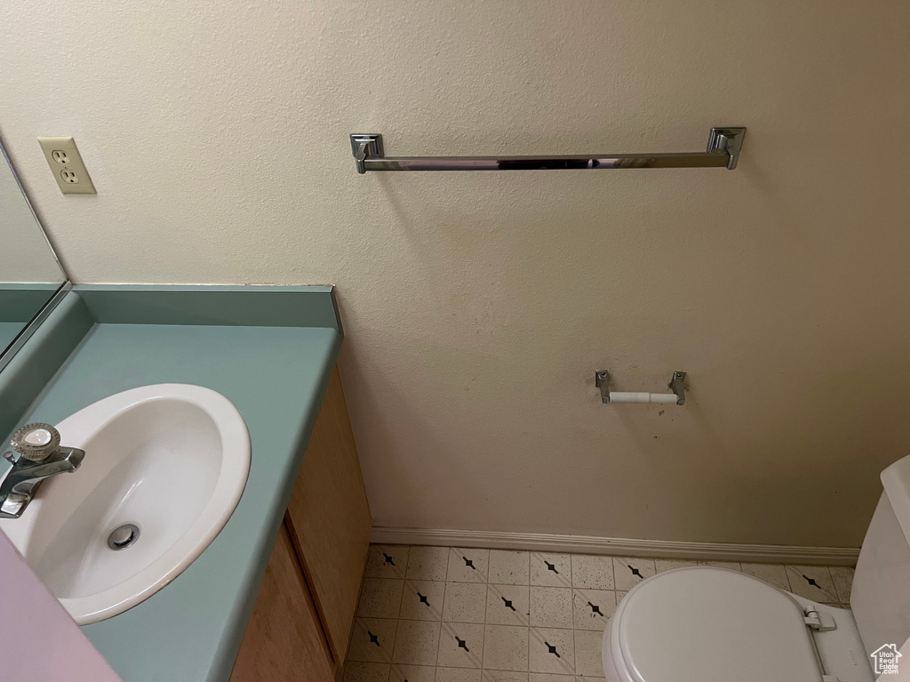 Bathroom featuring toilet, baseboards, and vanity
