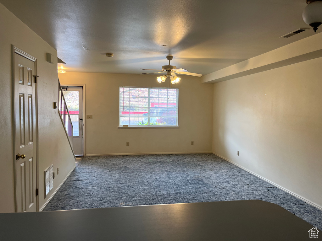 Empty room with a ceiling fan, visible vents, a wealth of natural light, and carpet