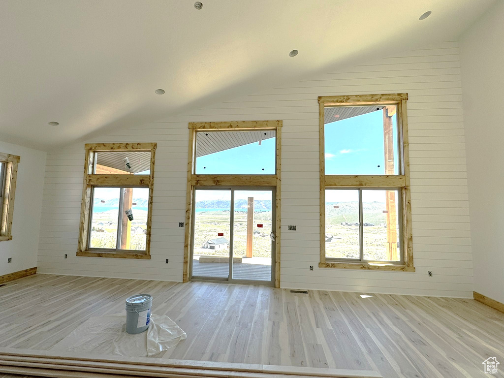 Doorway to outside with vaulted ceiling, plenty of natural light, and wood finished floors