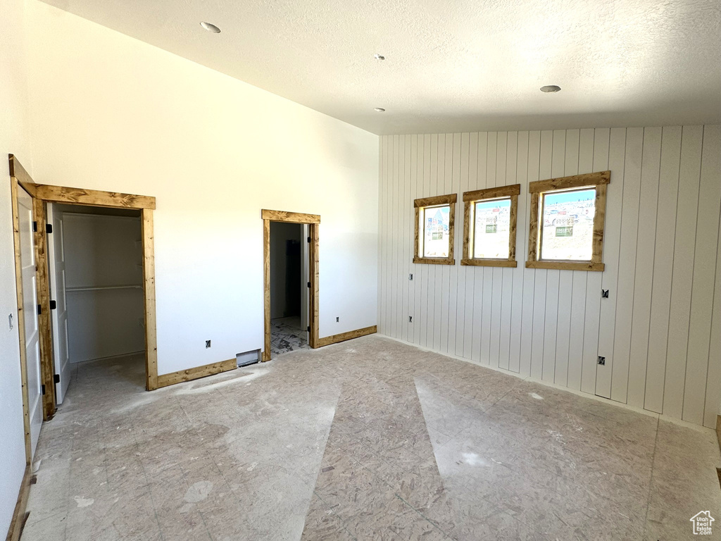 Unfurnished bedroom with baseboards, a textured ceiling, lofted ceiling, and a spacious closet