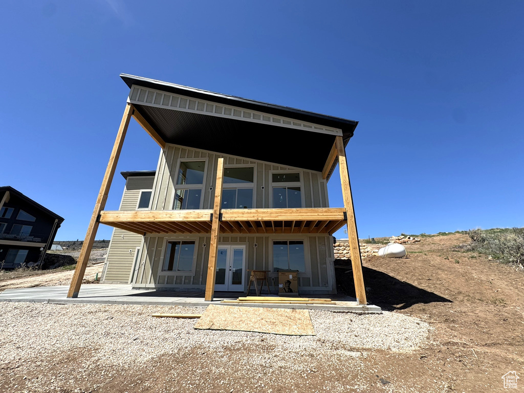 Back of house featuring board and batten siding, french doors, and a patio area