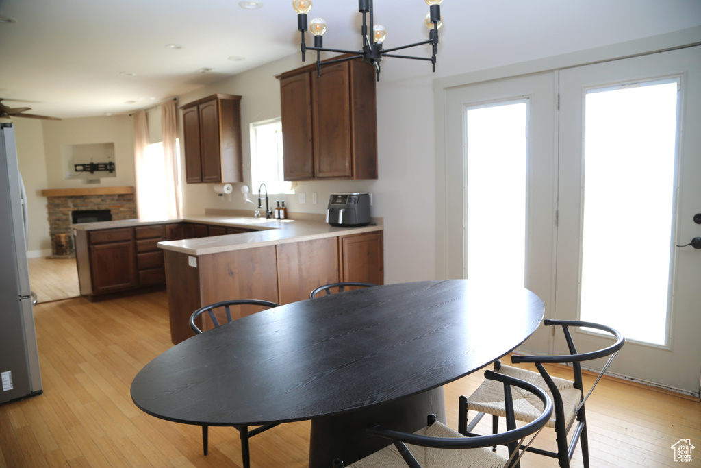 Kitchen featuring a peninsula, freestanding refrigerator, light wood-type flooring, a sink, and a chandelier