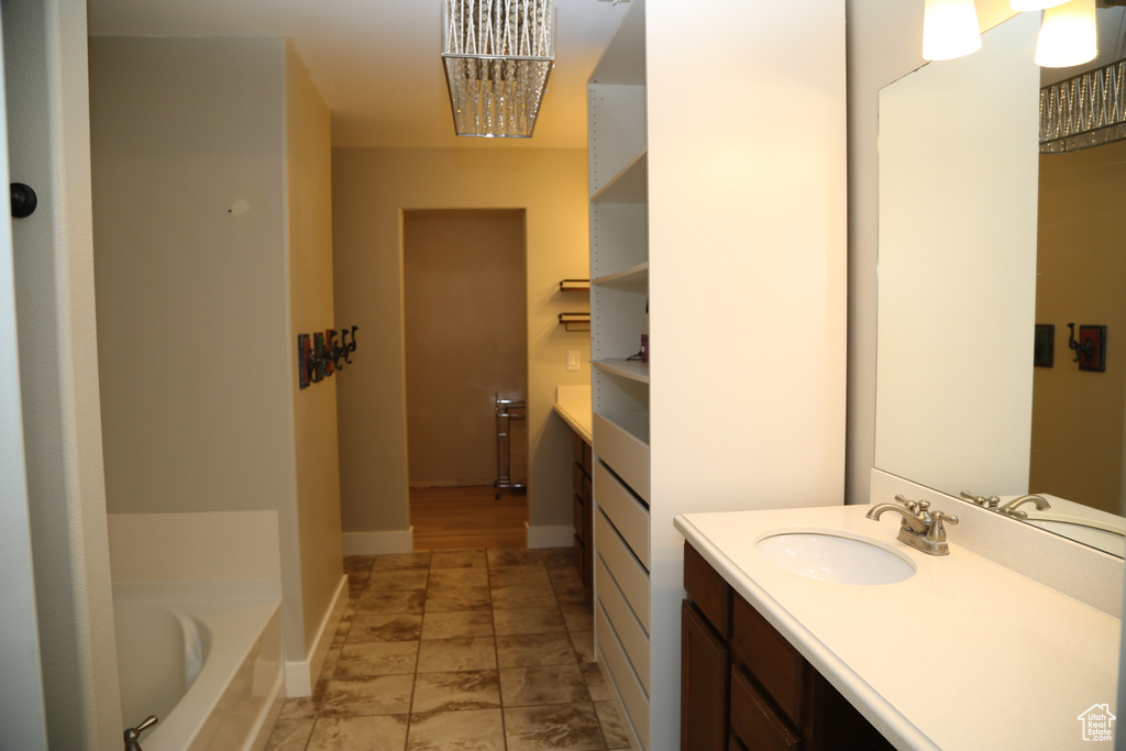 Full bathroom with vanity, a bath, and baseboards