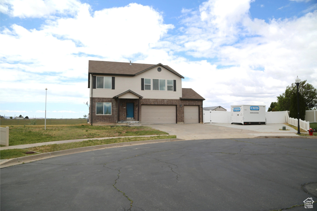 View of front of property featuring driveway, brick siding, and a garage