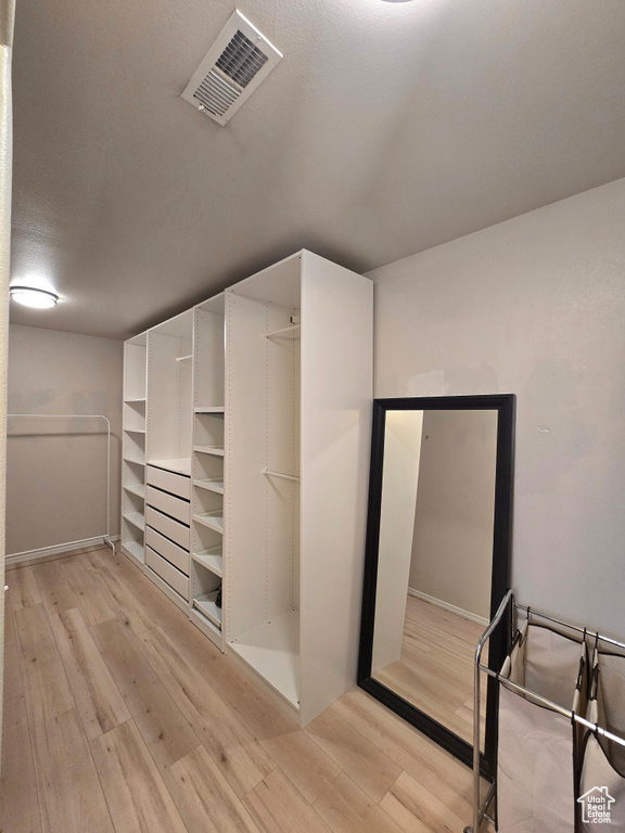 Spacious closet with light wood-style flooring and visible vents
