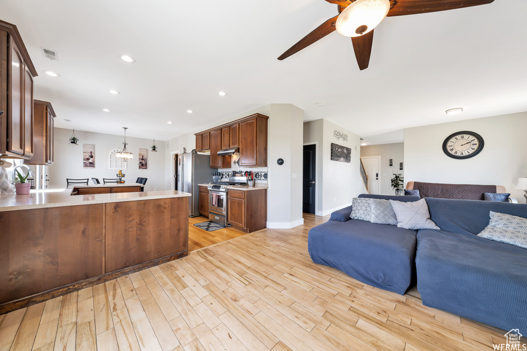 Living area featuring visible vents, baseboards, ceiling fan with notable chandelier, light wood-style floors, and recessed lighting