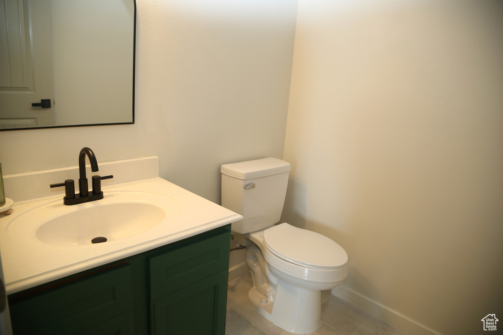 Half bathroom featuring vanity, toilet, and baseboards