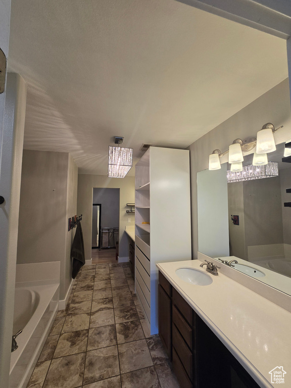 Bathroom featuring vanity, a bath, and baseboards