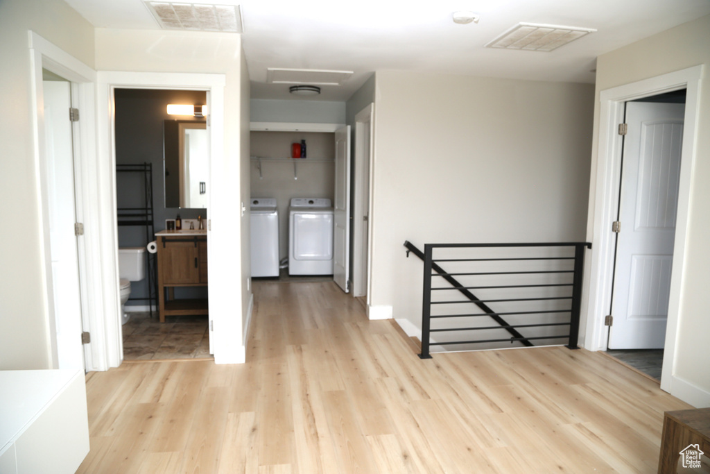 Corridor featuring an upstairs landing, separate washer and dryer, light wood-type flooring, and baseboards