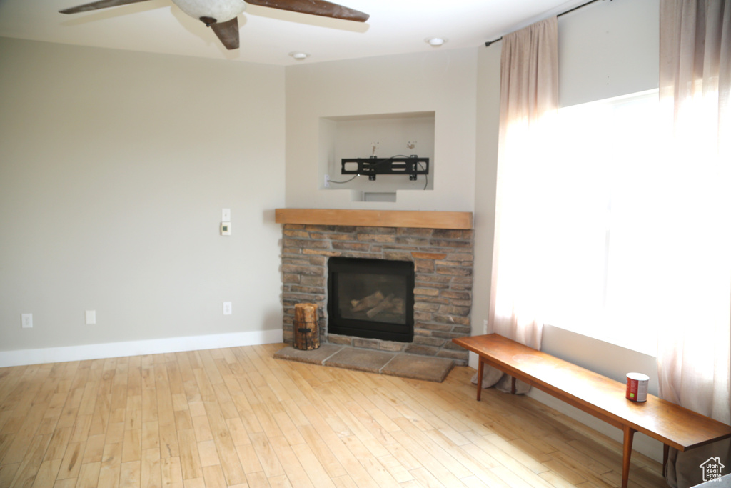 Living room with a fireplace, wood finished floors, a ceiling fan, and baseboards
