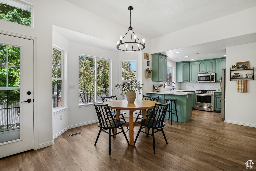 Dining area with a chandelier, plenty of natural light, dark wood finished floors, baseboards, and recessed lighting