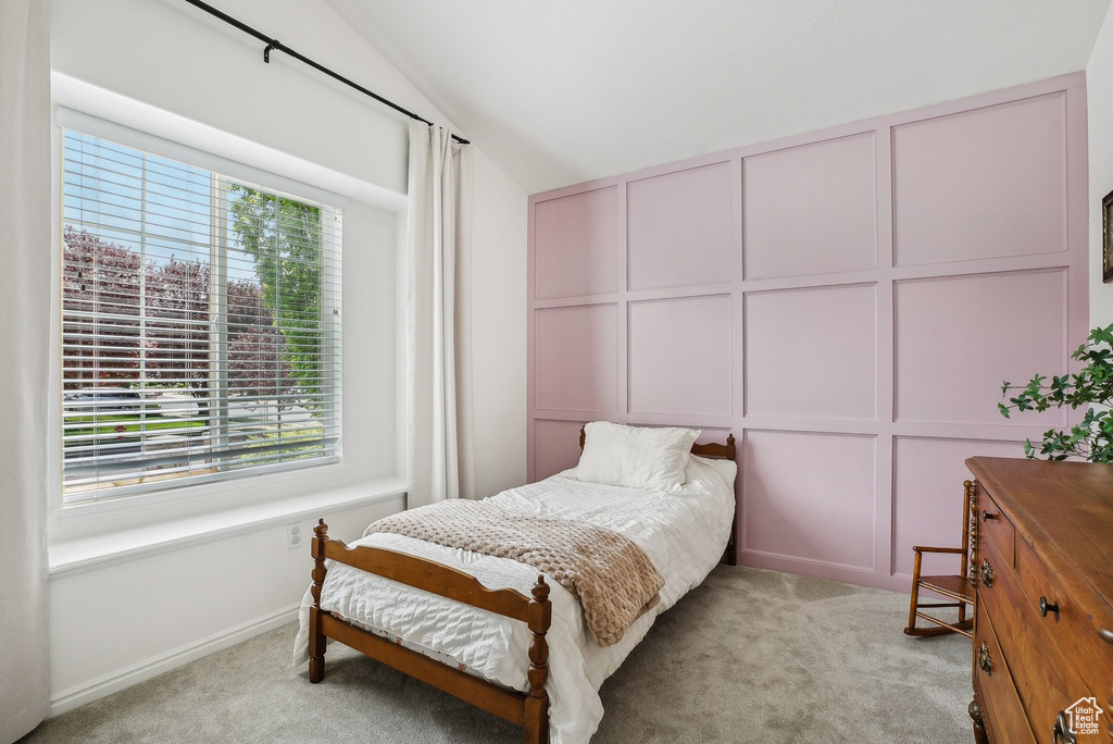 Bedroom with multiple windows, light carpet, and lofted ceiling