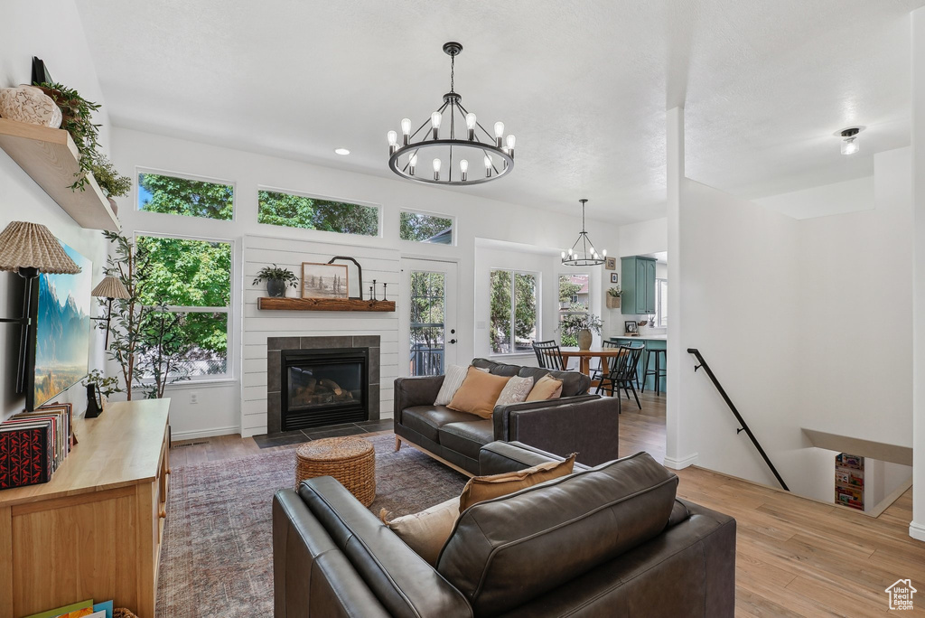Living room with a chandelier, wood finished floors, a fireplace with flush hearth, and plenty of natural light