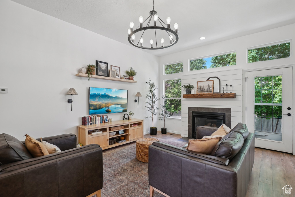 Living room featuring a chandelier, a fireplace with flush hearth, wood finished floors, and recessed lighting
