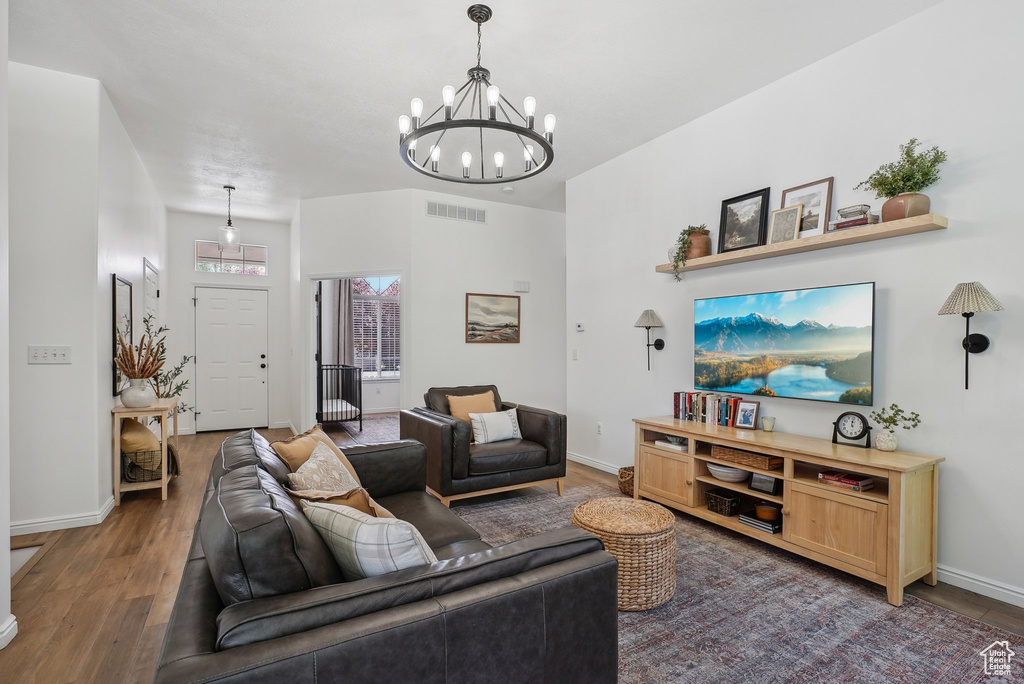 Living room featuring wood finished floors, a chandelier, and baseboards