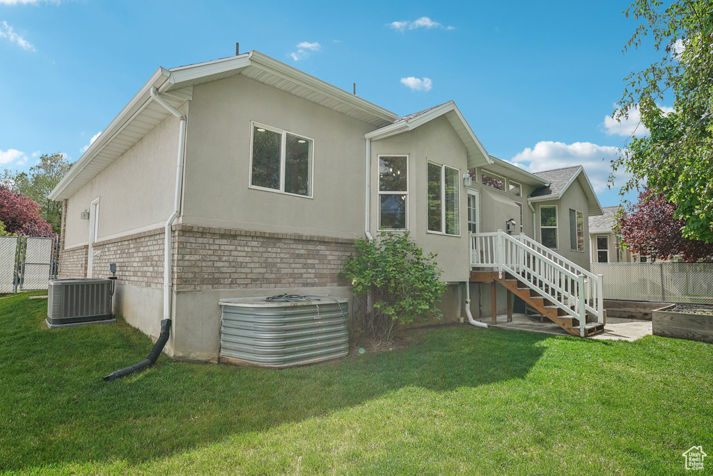 Back of property with stucco siding, cooling unit, and brick siding