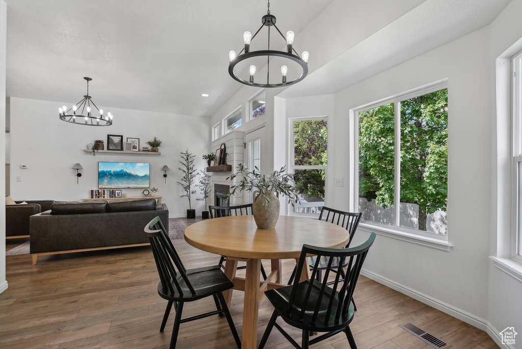 Dining room featuring a chandelier, healthy amount of natural light, wood finished floors, and recessed lighting