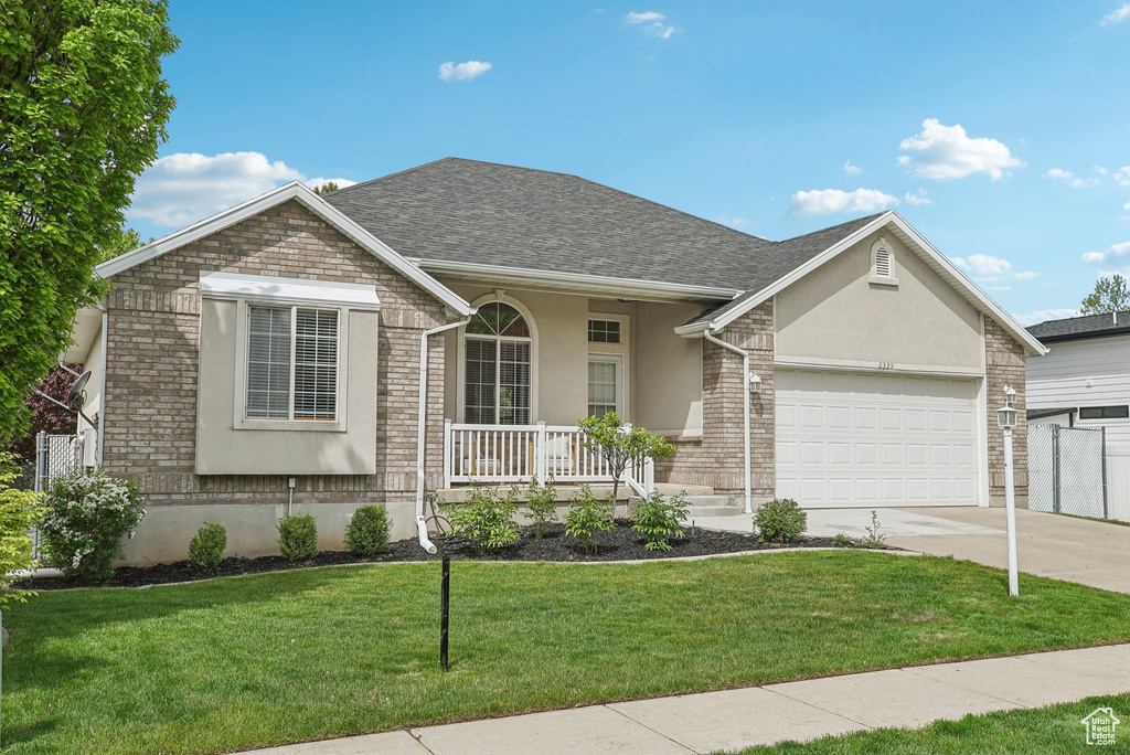 Single story home with covered porch, stucco siding, a garage, concrete driveway, and a front yard