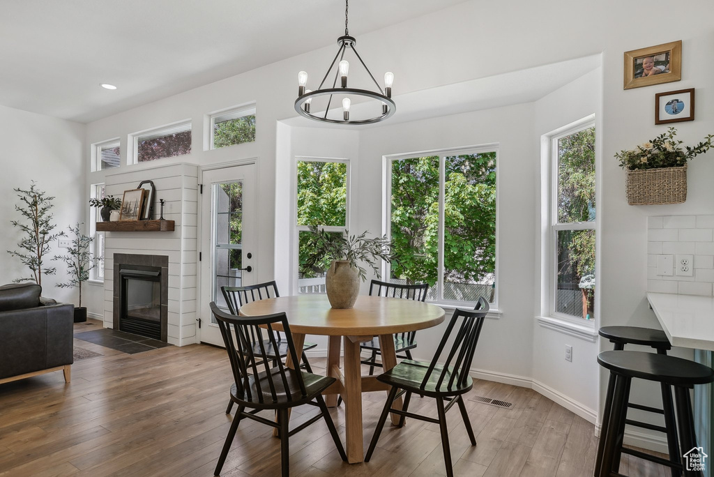 Dining room with plenty of natural light, light wood-style flooring, a chandelier, a fireplace with flush hearth, and recessed lighting