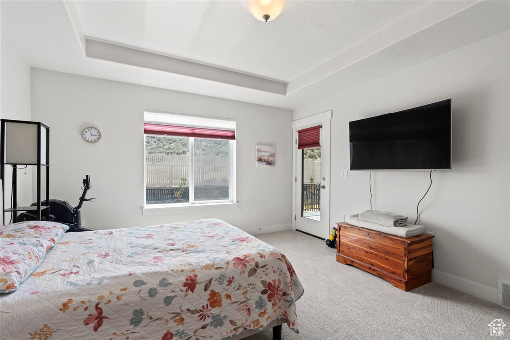 Bedroom featuring visible vents, access to exterior, a raised ceiling, baseboards, and carpet