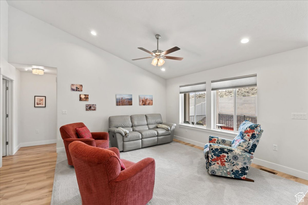 Living room with light wood-style floors, baseboards, ceiling fan, and lofted ceiling