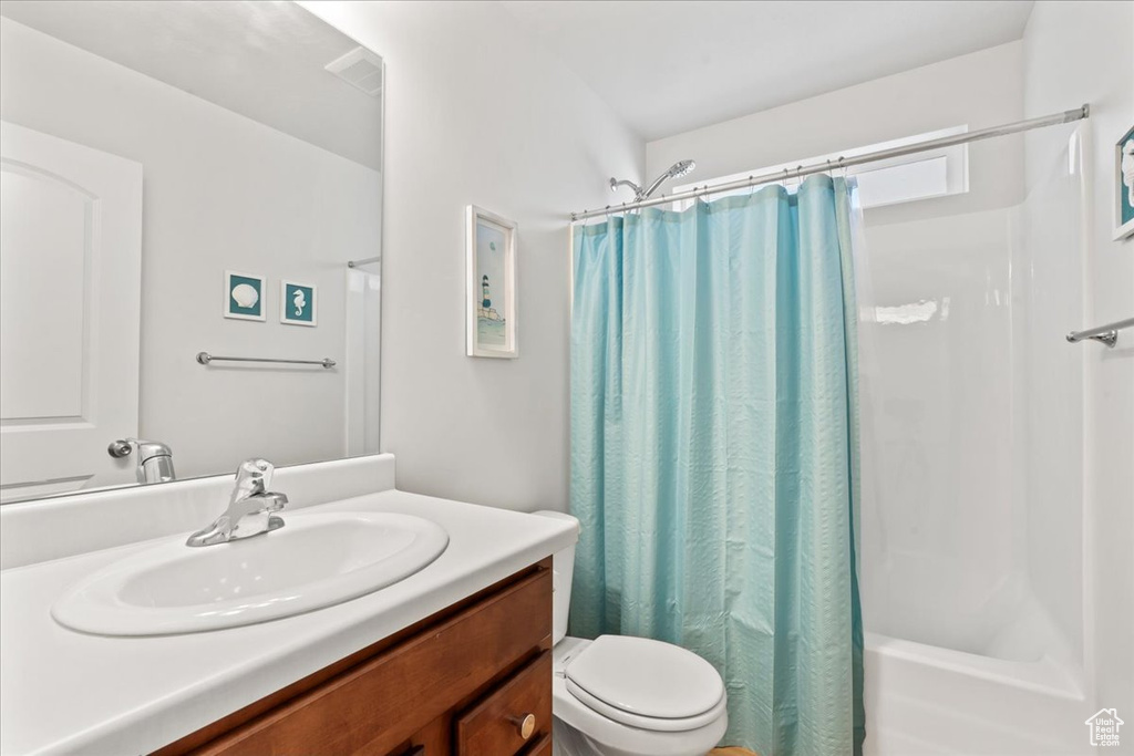 Bathroom featuring vanity, shower / bath combo, and toilet