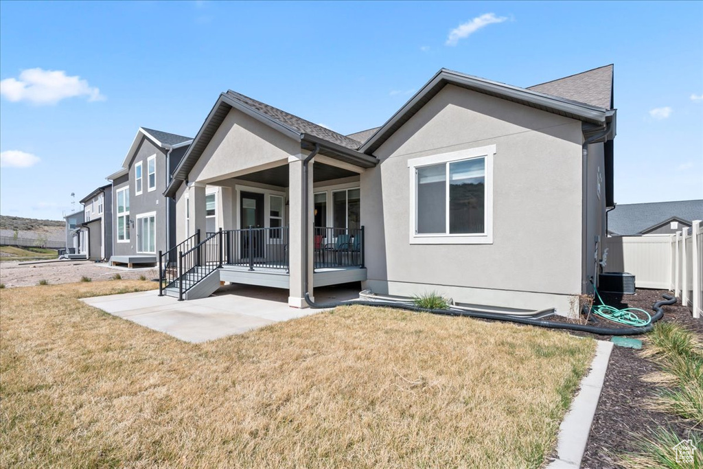 Rear view of property with a lawn, fence, and stucco siding