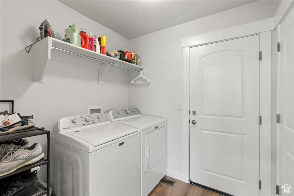 Clothes washing area featuring washer and dryer, a textured ceiling, laundry area, and dark wood-style floors
