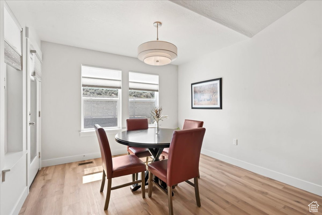 Dining area with baseboards, visible vents, and light wood finished floors