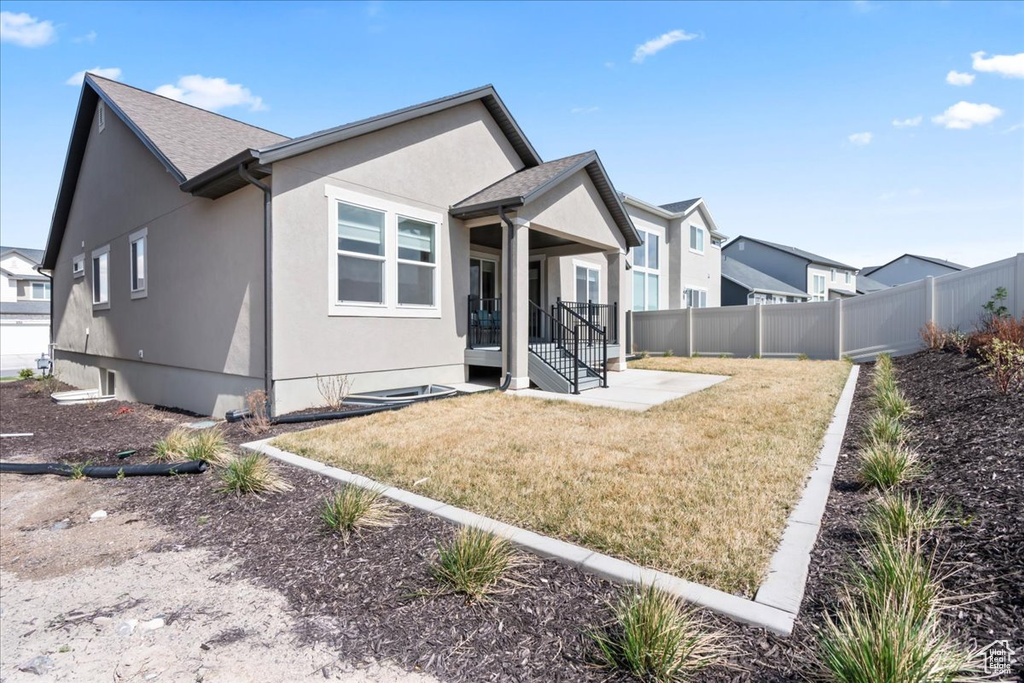 Rear view of house featuring stucco siding, a patio area, fence, and a yard