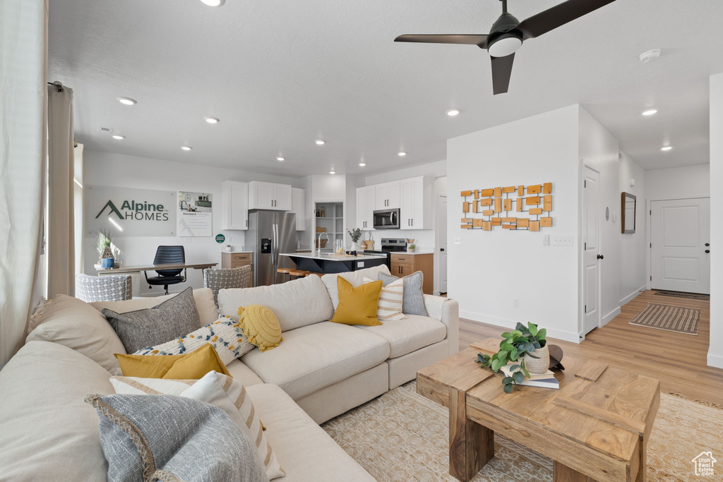 Living room featuring baseboards, a ceiling fan, recessed lighting, and light wood-style flooring