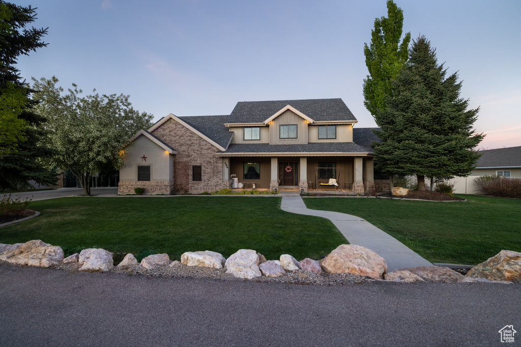Craftsman-style home featuring a porch, a front lawn, and stone siding
