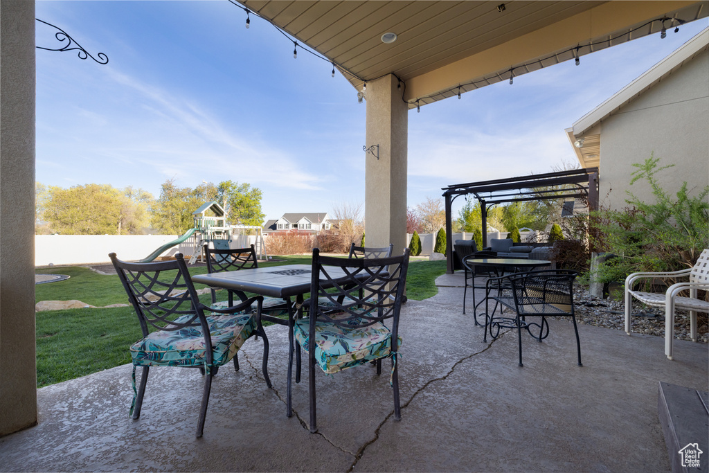 View of patio / terrace with a pergola, a fenced backyard, outdoor dining space, and a playground