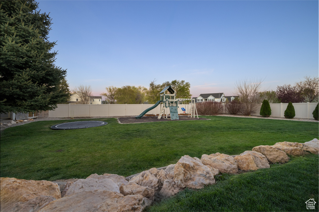 View of yard with a fenced backyard, a playground, and a trampoline