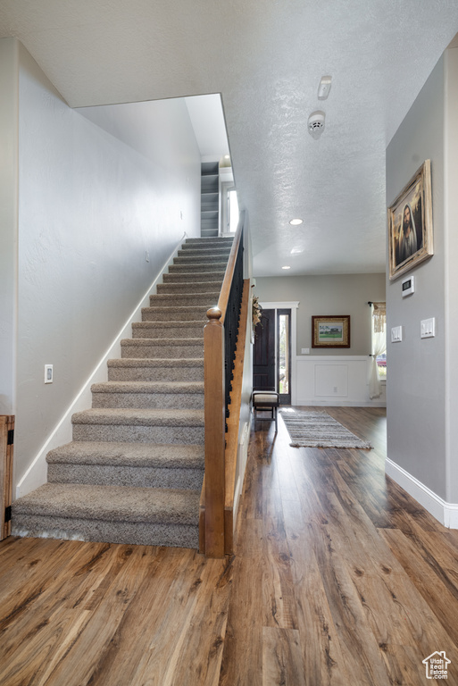 Stairway featuring a textured ceiling and wood finished floors