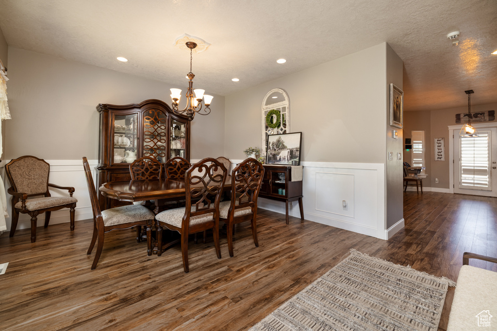 Dining area with wainscoting, dark wood-type flooring, recessed lighting, and a notable chandelier