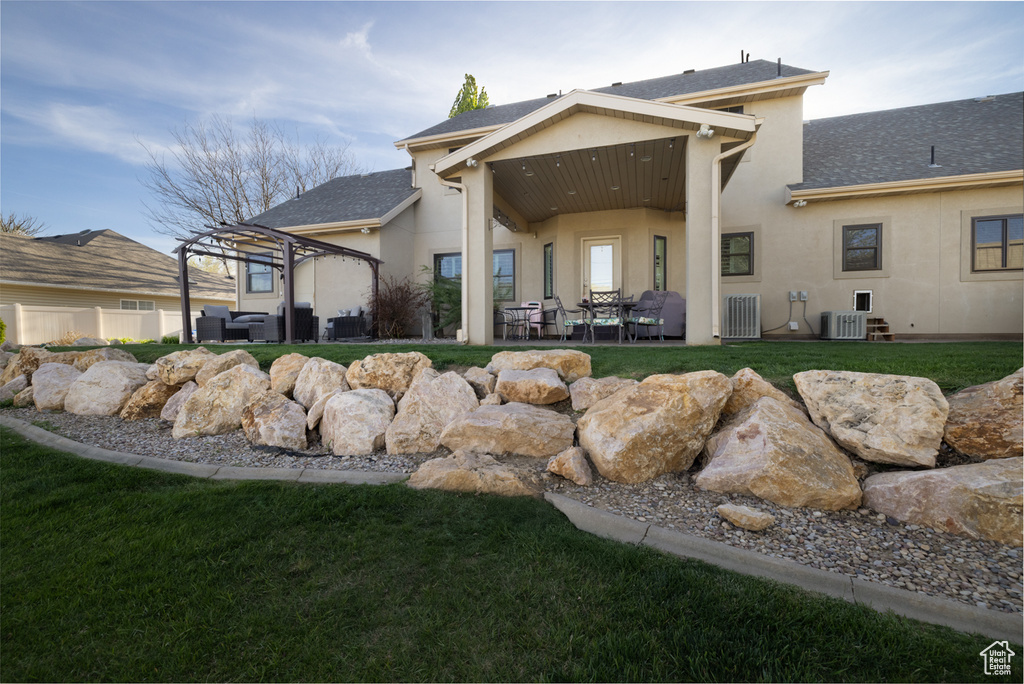 Rear view of property with a patio area, central AC, an outdoor hangout area, a yard, and stucco siding