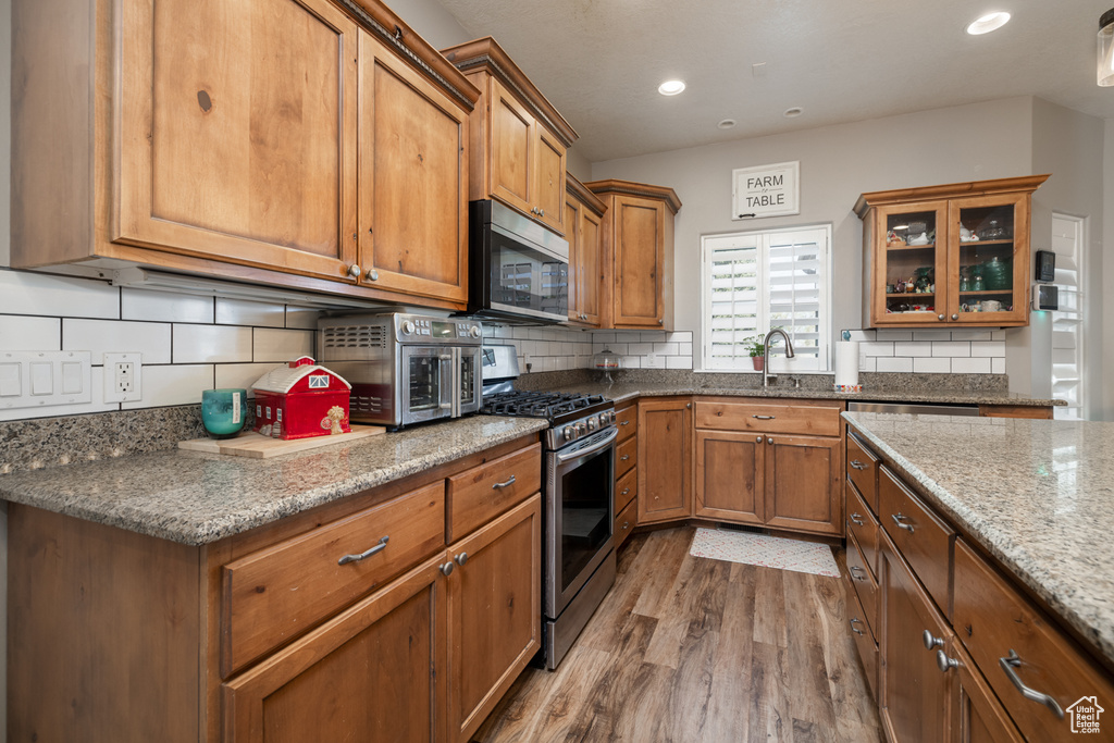 Kitchen featuring tasteful backsplash, stainless steel appliances, brown cabinets, and wood finished floors
