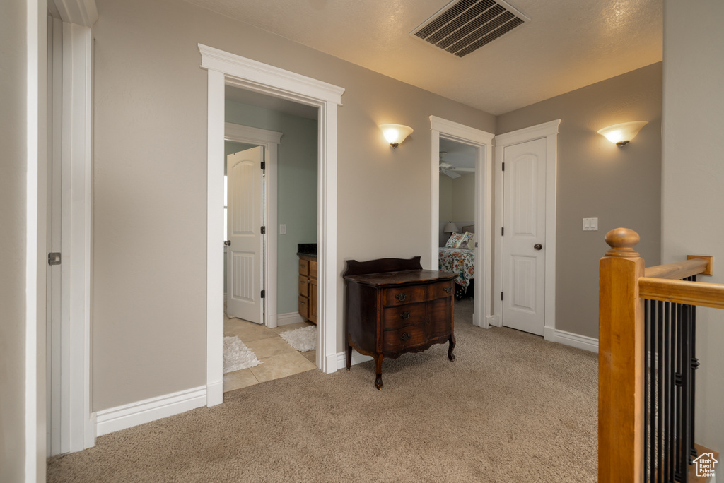 Corridor with visible vents, baseboards, carpet floors, and an upstairs landing