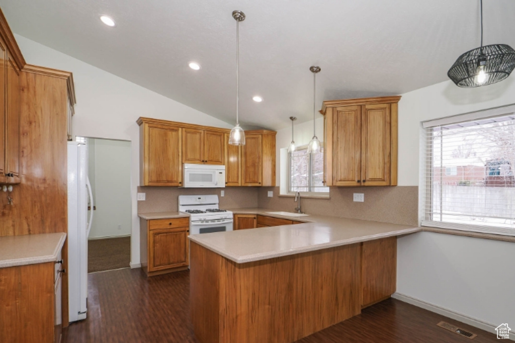 Kitchen featuring dark wood-type flooring, a sink, a peninsula, and white appliances