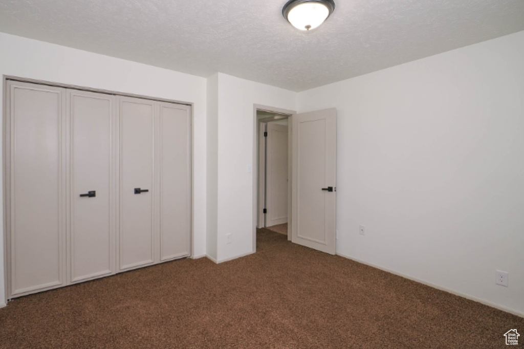 Unfurnished bedroom with a closet, carpet flooring, and a textured ceiling