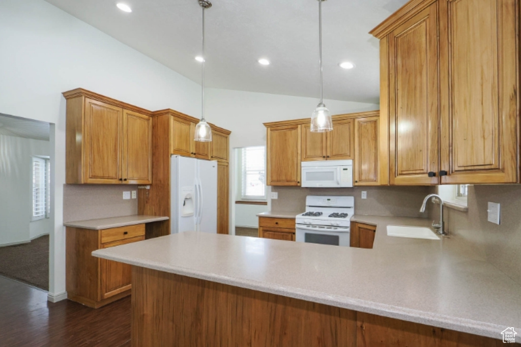 Kitchen featuring white appliances, a peninsula, a sink, and light countertops