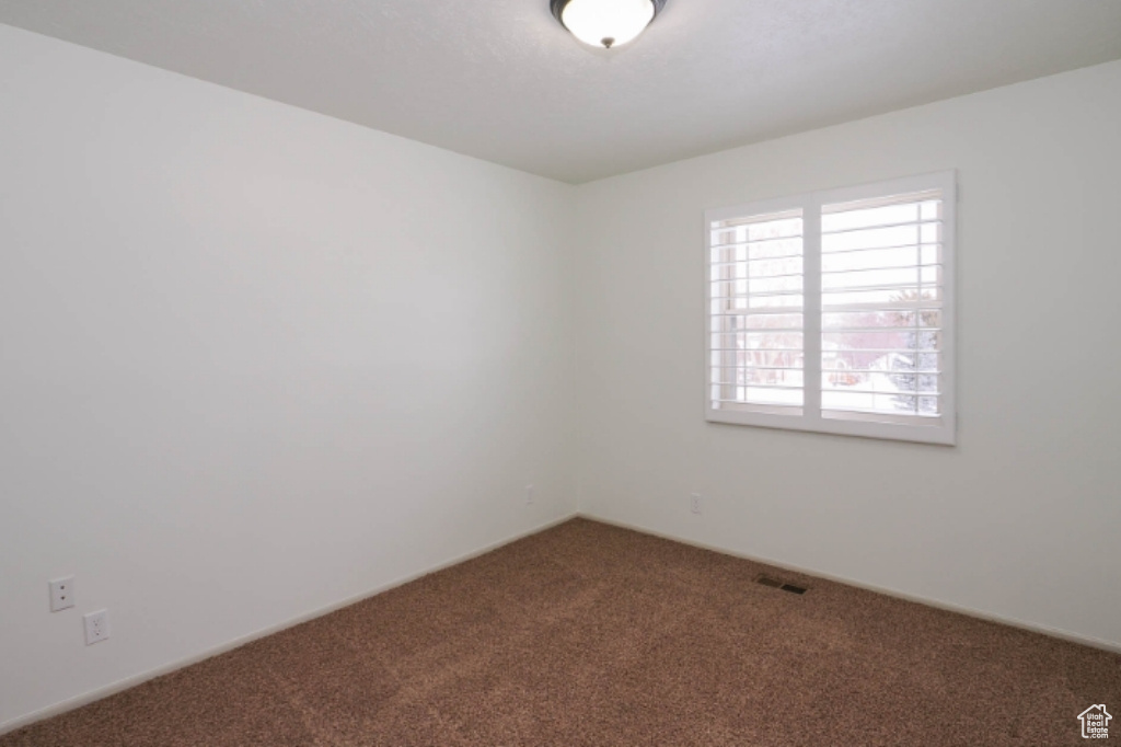 Empty room with carpet flooring and visible vents